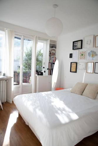 une chambre blanche avec un grand lit et une fenêtre dans l'établissement Triplex lumineux avec balcon - 500m Champs Elysées, à Paris