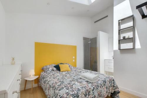 - une chambre avec un lit et un mur jaune dans l'établissement L'Ormeau - Charmant appt pour 4, à Toulouse