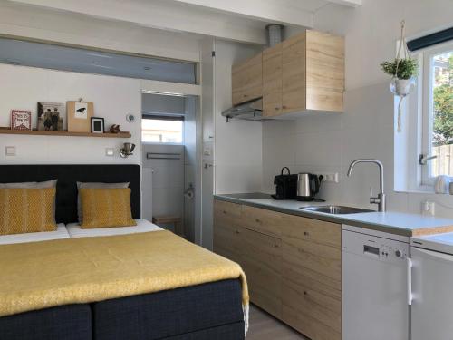 a small kitchen with a bed and a sink at DeZwarteRuiter in Callantsoog
