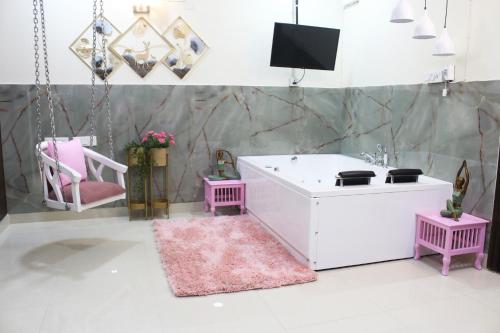 a room with a tub and two chairs and a tv at Modern Jacuzzi Hot Tub 1BHK Suite South Delhi 3 in New Delhi