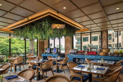 a restaurant with tables and chairs and a bar at The Proud Karon Beach Phuket Trademark Collection By Wyndham in Karon Beach