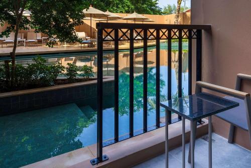a balcony with a table and a swimming pool at The Proud Karon Beach Phuket Trademark Collection By Wyndham in Karon Beach