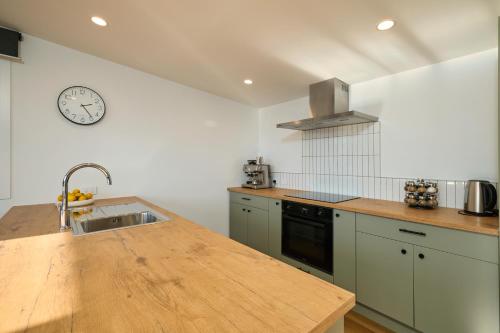 a kitchen with a sink and a clock on the wall at Modern Mountain Views Sunny in Kaikoura