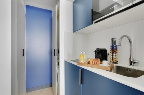 une cuisine avec des armoires bleues et un évier dans l'établissement SERENERS - Charming Serviced Apartments - Bastille, à Paris