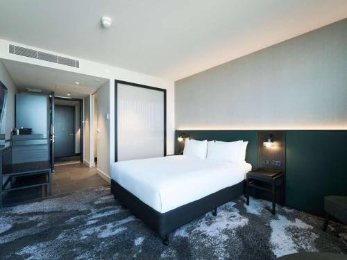 a bedroom with a white bed and a large window at Novotel Melbourne Airport in Melbourne