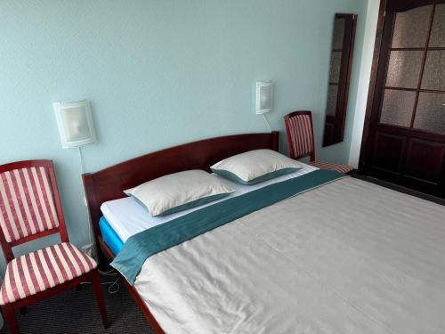a bedroom with a large bed with two chairs at Baskervilu Muiža in Sērenes