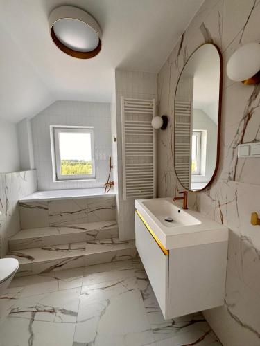 a white bathroom with a sink and a mirror at Apartamenty przy Winnicy in Busko-Zdrój