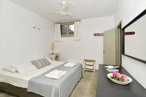 a white bedroom with a bed and a bowl of flowers on a table at Villa Ourania in Kampos Paros