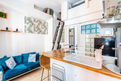 Il comprend une cuisine et un salon doté d'un canapé bleu. dans l'établissement GuestReady - Beau Séjour près de Canal St Martin, à Paris