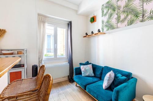un salon avec un canapé bleu et une fenêtre dans l'établissement GuestReady - Beau Séjour près de Canal St Martin, à Paris