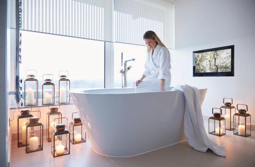 a woman sitting in a bath tub in a bathroom with candles at COMO Metropolitan London in London