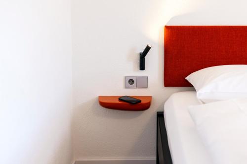 a bed with a red headboard and a phone on a shelf at schlossmühle - lean luxury boutique hotel in Glottertal