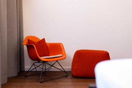 an orange chair sitting next to a white wall at schlossmühle - lean luxury boutique hotel in Glottertal