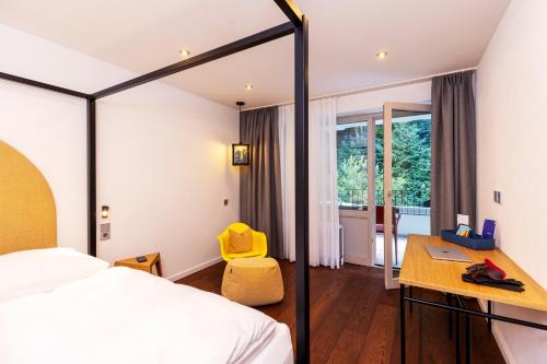 a bedroom with a bed and a desk with a yellow chair at schlossmühle - lean luxury boutique hotel in Glottertal