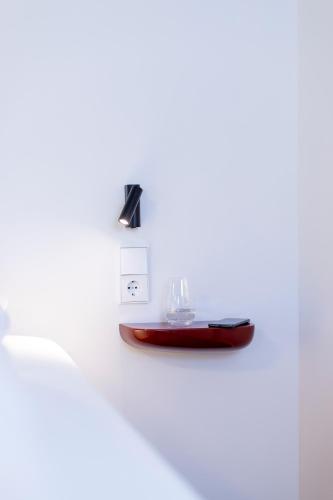 a light on a white wall with a table at schlossmühle - lean luxury boutique hotel in Glottertal