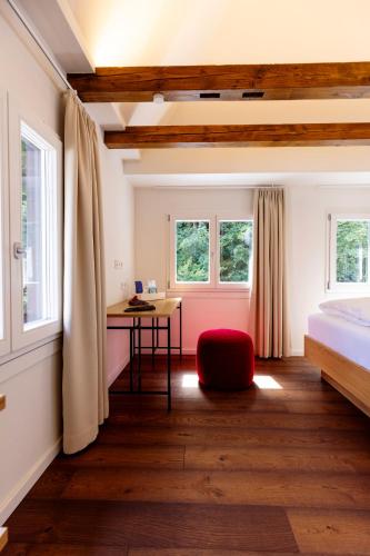 a bedroom with a bed and a desk and windows at schlossmühle - lean luxury boutique hotel in Glottertal