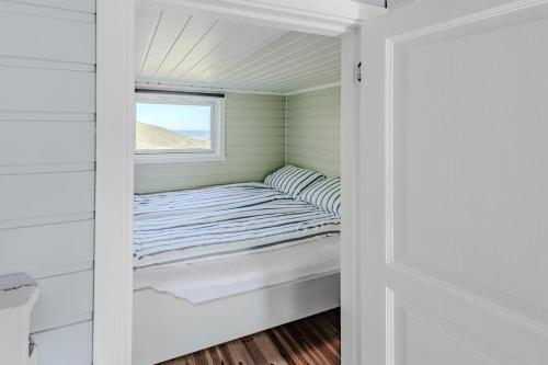 a bed in a small room with a window at HeiaHytta Fredvang in Fredvang