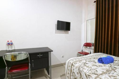 a bedroom with a desk and a bed with a chair at Saloka Guest House & Residence in Cimahi