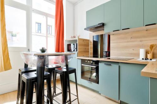 une cuisine avec des placards bleus et une table avec des tabourets dans l'établissement Modern 1BR Flat in the heart of Lille, à Lille