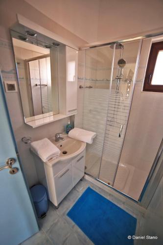 a white bathroom with a shower and a sink at Surf Beach Apartments in Palekastron