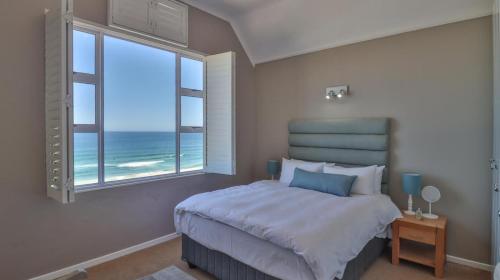 a bedroom with a large bed with a view of the ocean at House Susan Pardew Hersham in Great Brak River