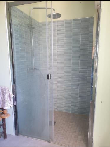 une douche avec une porte vitrée dans une salle de bain dans l'établissement Maison de famille, à Montséret