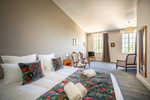 a bedroom with a large white bed with flowers on it at Le Prieuré Corrèze in Corrèze