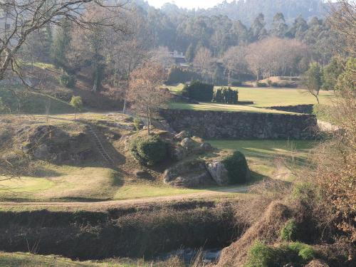 a view of a golf course with a stone wall at Rilhadas Casas de Campo in Fafe