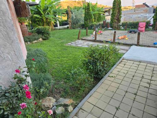 a backyard with a garden with pink flowers and a fence at Boutique Hotel Colosseo in Sandanski