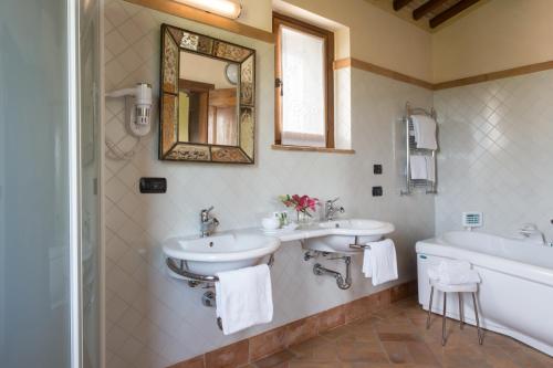 Un baño con dos lavabos, una bañera y un espejo. en Valle di Assisi Villa Privata, en Tordandrea