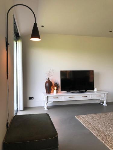 a living room with a flat screen tv on a white table at Smithoes in Groot-Agelo