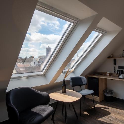 a room with two chairs and a table and two windows at Hotel Harmony in Ghent