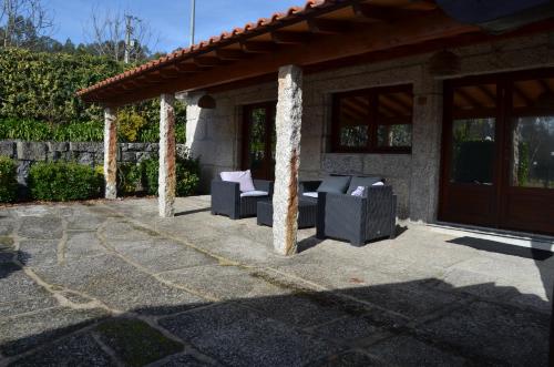 a patio with two chairs and a television at Rilhadas Casas de Campo in Fafe