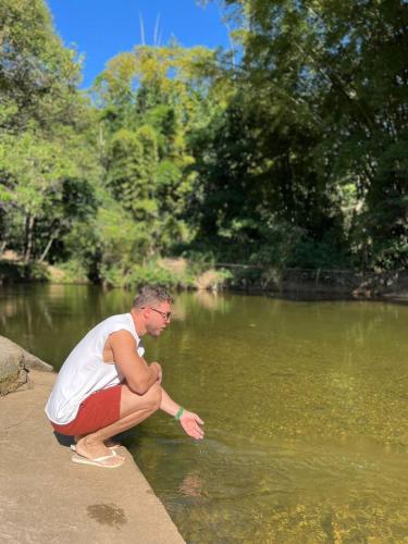 a man sitting on the edge of a body of water at Pousada Dom Dimitri in Lumiar