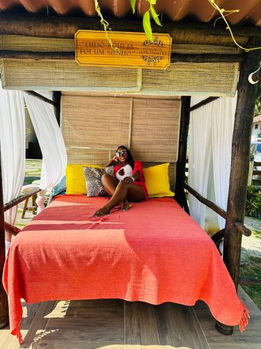 a woman sitting on a bed with a red blanket at Pousada Dom Dimitri in Lumiar
