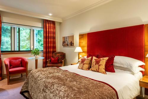 a bedroom with a large bed with a red headboard at Mallory Court Country House Hotel & Spa in Leamington Spa