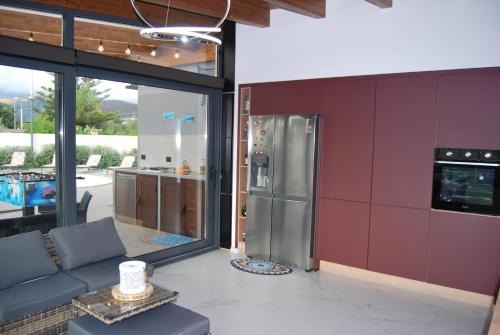 a kitchen with a couch and a stainless steel refrigerator at Villa El Secreto Luxury con piscina, sauna e idromassaggio, vicina al mare e montagna in Borgetto