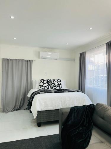 a white bedroom with a bed and a couch at Easy Living Apartment 2 in Rundu