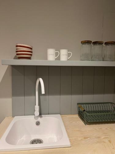 a kitchen counter with a sink and cups on a shelf at Calendula Hotel & Apartaments in Sant Feliu de Guixols