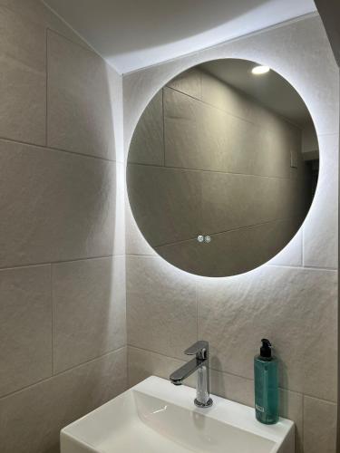 a bathroom with a sink and a round mirror at Calendula Hotel & Apartaments in Sant Feliu de Guixols