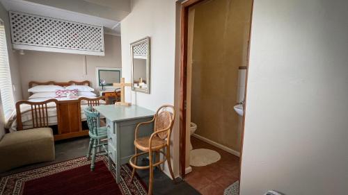 a room with a bed and a table and chairs at Holte vir die Voet Akkommodasie in Gansbaai