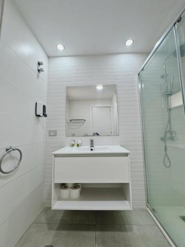 a white bathroom with a sink and a shower at Sea View Cura Marina 415 in Playa del Cura
