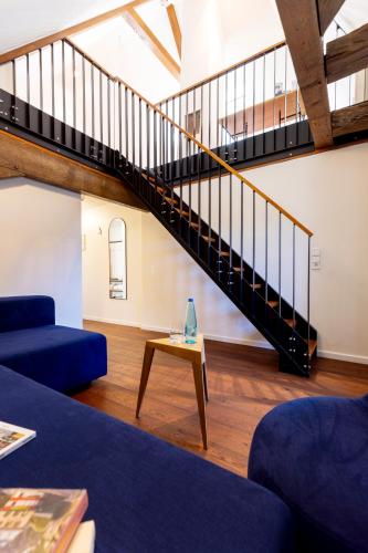 a living room with a blue couch and a staircase at schlossmühle - lean luxury boutique hotel in Glottertal