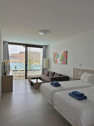 a hotel room with two beds and a living room at Sea View Cura Marina 415 in Playa del Cura