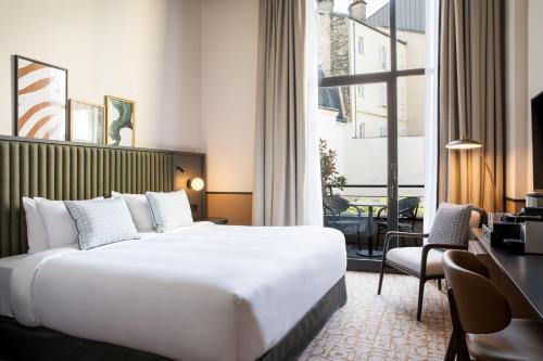 a hotel room with a large bed and a desk at Le Parchamp, a Tribute Portfolio Hotel, Paris Boulogne in Boulogne-Billancourt