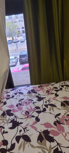 a bedroom with a bed with a floral bedspread with a window at Home Away Apartment in Abu Dhabi