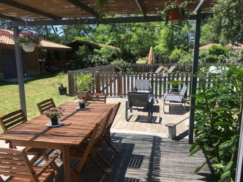 une table et des chaises en bois sur une terrasse dans l'établissement Maison typique en lisière de forêt au calme, à Moustey
