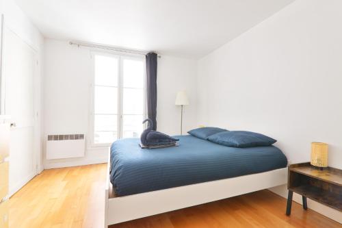 - une chambre blanche avec un lit et des oreillers bleus dans l'établissement Appartement Quartier Chatelet Les Halles 2 Free Netflix, à Paris