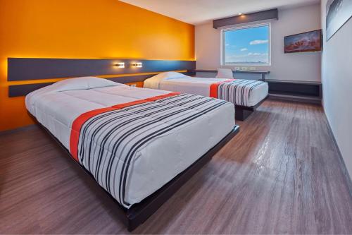 two beds in a room with orange walls at City Express Junior by Marriott San Luis Potosi Carranza in San Luis Potosí