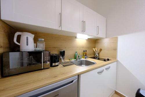 une cuisine avec un évier et un micro-ondes dans l'établissement Rouen Gare - Chez Guillaume, à Rouen